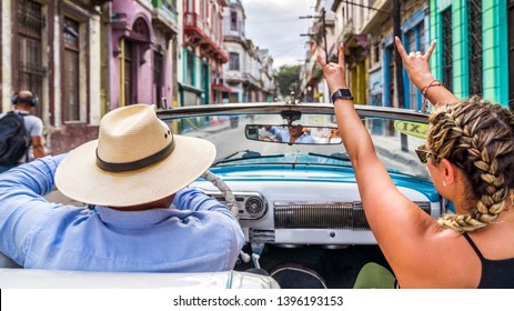 Havana Cuba. Woman Smiling Happy Enjoying Car Road Trip Travel Vacation, Holding Hands Up In Blue Vintage Convertible Car On The Colourful Streets Of Havana.