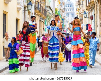 HAVANA,CUBA- JANUARY 24,2015 : Colorful band of musicians and dancers on stilts on a narrow Old Havana street