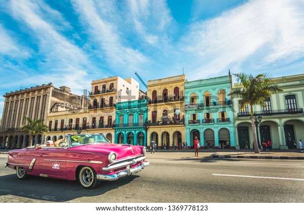 HAVANA,CUBA - MARCH 18,2019: A pink American\
classic car next to El Capitolio in Havana, La Habana, Cuba, West\
Indies, Caribbean, Central\
America