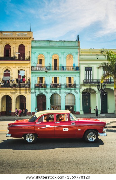 HAVANA,CUBA - MARCH 18,2019: A red American\
classic car next to El Capitolio in Havana, La Habana, Cuba, West\
Indies, Caribbean, Central\
America