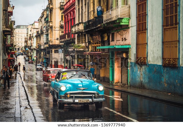 HAVANA,CUBA - MARCH 18,2019: Turquoise vintage\
taxi in the rain, La Habana, Havana, Cuba, West Indies, Caribbean,\
Central America