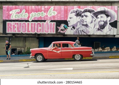 HAVANA,CUBA - MAY 12,2015 :  Vintage American Car Next To A Poster Supporting The Cuban Revolution