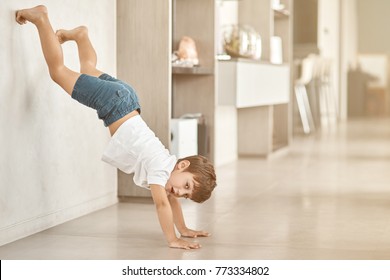 Have fun. Cute little boy standing near wall upside down while resting at home - Shutterstock ID 773334802