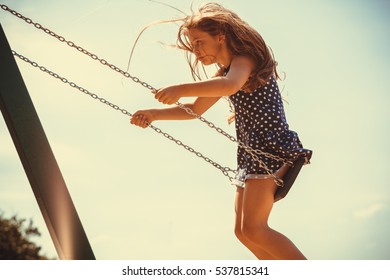 Have fun and leisure concept. Long haired enjoyable girl swinging outdoor in garden playground. Lovely child playing on swing-set. - Powered by Shutterstock