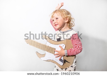 have fun on party. little funny girl with DIY guitar. musical instrument handmade of cardboard in hands of child. Learning to play the guitar. musical school concept