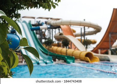 Have fun riding slides in an aquapark. Summer vacation entertainment ideas. Colorful slide variety and turquoise swimming pool at a hotel. Water reflection in empty aqua park during pandemic isolation
