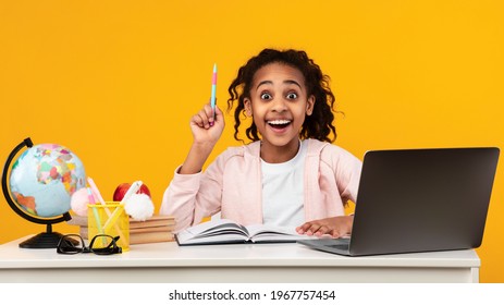 I Have Great Idea. Portrait Of Emotional African American Girl Pointing Pen Up, Thinking And Finding Inspiration Or Solution, Sitting At Desk With Laptop And Doing Homework. Excited Black Kid Learning