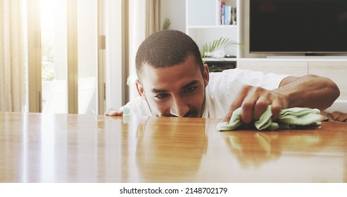 I Have To Pay Attention To Detail. Shot Of A Focused Young Man Cleaning The Surface Of A Table With Cleaning Equipment At Home During The Day.