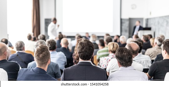 I Have A Question. Group Of Business People Sitting At The Chairs In Conference Hall. Businessman Standing Up Asking A Question. Conference And Presentation. Business And Entrepreneurship.