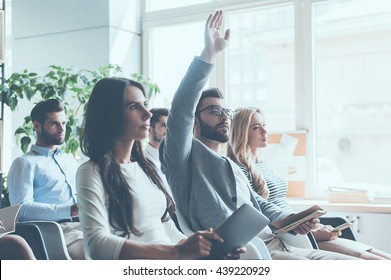 I have a question! Group of young people sitting on conference together while one man raising his hand  - Shutterstock ID 439220929