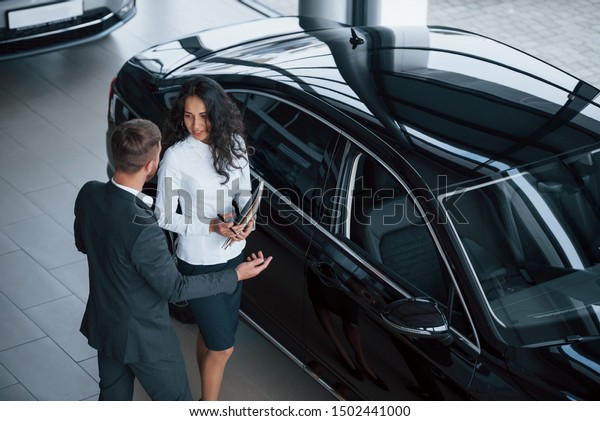 I have some\
questions. Female customer and modern stylish bearded businessman\
in the automobile saloon.