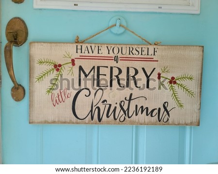 A have yourself a merry Christmas sign hanging on a blue door. 