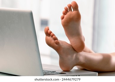I haven't mood to work today. Close up cheerful young business girl put her bare feet on the laptop, she does not want to work at office.