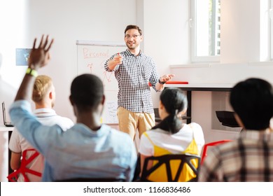 Having Answers. Smiling Emotional Businessman Conducting A Workshop And One Student Raising His Hand While Having Questions