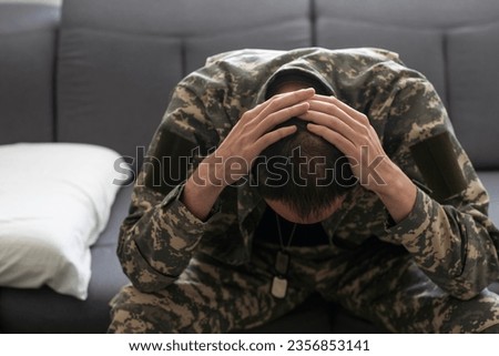 Having flashbacks. Post traumatic stress disorder. Soldier in uniform sitting indoors.