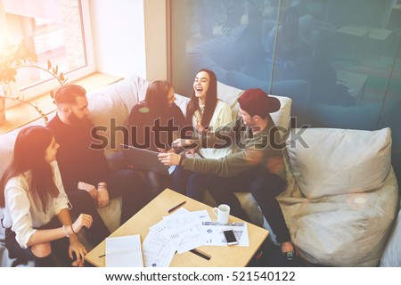 Having fun during preparing successful business project with skilled colleagues in friendly atmosphere,using digital devices and internet. University students working on coursework 