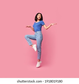 Having Fun. Full body length portrait of happy young asian woman jumping, dancing and looking aside at free space, being in a good mood, isolated over bright pink background, studio shot