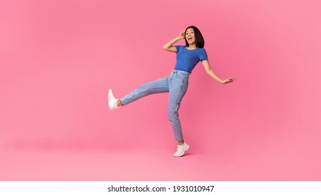 Having Fun. Full Body Length Shot Of Happy Cheerful Young Asian Woman Jumping, Dancing And Fooling Around, Being In A Good Mood, Celebrating Triumph, Isolated Over Bright Pink Studio Background