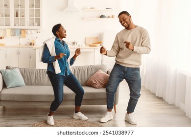 Having Fun. Full body length portarit of excited young black couple dancing and fooling around. Emotional happy African American man and woman enjoying favorite music together at home - Powered by Shutterstock