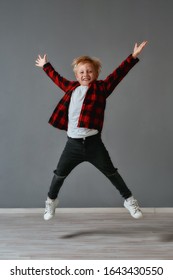 Having fun. Full length portrait of a cute and excited little boy in casual clothes jumping in the dance studio. Looking at camera. Choreography class. Happy children. Motion