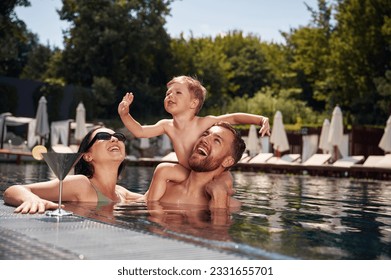 Having fun. Happy family of father, mother and son are in the pool.