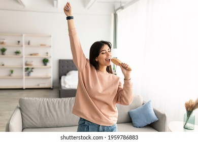 Having Fun. Portrait of cheerful positive young woman holding and using hairbrush as mic, singing her favorite song and dancing at home. Millennial lady pretending to be famous singer star - Powered by Shutterstock