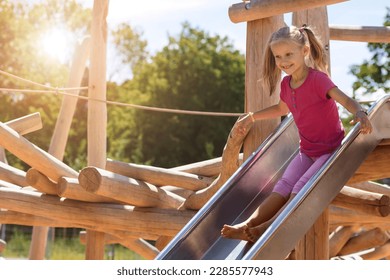 Having fun Sliding on Playground Outdoors. Little Girl Child Riding Slide Swings on Modern Wooden Playground. Happy Weekend with Children in Park.  - Powered by Shutterstock