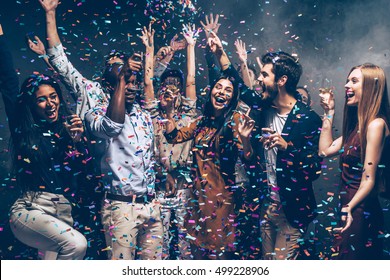 Having Fun Together. Group Of Beautiful Young People Throwing Colorful Confetti And Looking Happy