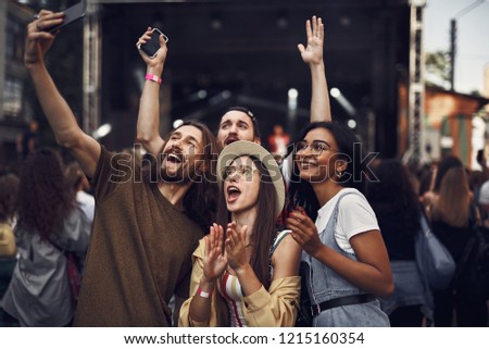 Having fun. Waist up portrait of young people taking photo with smartphone while enjoying concert