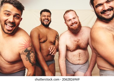 Having fun while shirtless. Three happy men smiling at the camera while wearing underwear in a studio. Body positive and self-confident men celebrating their natural bodies.