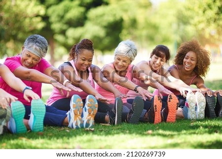 Having a laugh while limbering up. Shot of a group of people warming up outdoors.