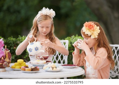 Having a make-believe tea party. Two young girls having a tea party in the backyard. - Powered by Shutterstock
