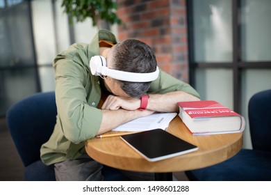 Having a nap. Tired dark-haired student wearing earphones having a nap after studying - Shutterstock ID 1498601288