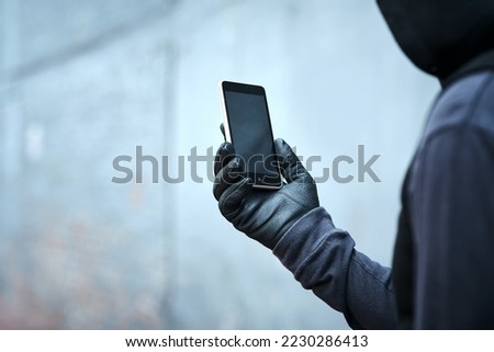 Having a quick look at where Ill strike next. Shot of a male burglar using his phone outdoors.