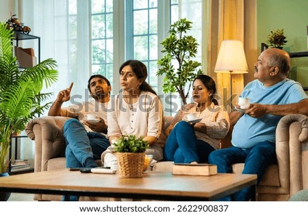 Having tea and discussing important topic, Indian family including senior parents, young adult son and daughter sitting on cozy sofa in modern living room engaged in serious family conversation