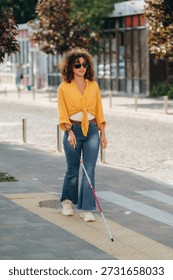 Having a walk, using white cane. A blind woman is in the modern city at daytime.