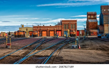 Havre, Montana USA - 1-31-2020: Train yard switching station with locomotive, maintenance facility, grain elevators, blue sky, industrial site 