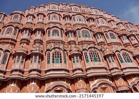 Hawa Mahal palace Jaipur, India. Five floor exterior built like honeycomb with small windows decorated with intricate latticework. Red and pink sandstone used and built like Hindu Rajput Architecture.