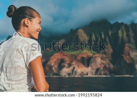 Hawaii cruise Asian tourist woman enjoying sightseeing looking at Na Pali Coast beach mountain landscape. Kauai island travel popular landmark, USA.
