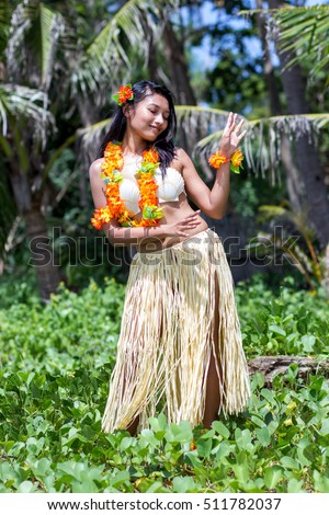 Hawaii hula dancer dancing in tropical nature. Ethnic girl in costume polynesian dancer on green background tropical vegetation. Hawaiian Woman dancing in front of palm trees.