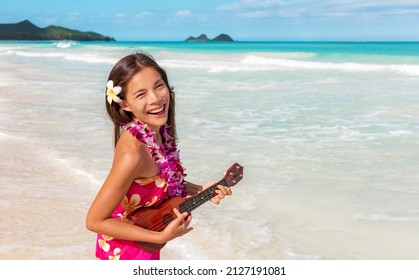 Hawaii luau ukulele hula dancing woman playing guitar on beach vacation with flower lei necklace and paero. Asian dancer smiling on hawaiian travel vacation.