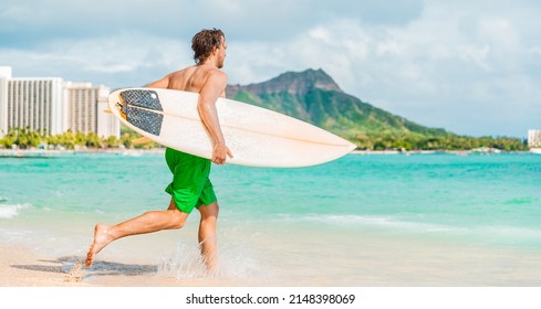 Hawaii surfing lifestyle young man sufer going to surf in blue ocean water in Honolulu, with Diamond Head in background. Oahu island travel vacation