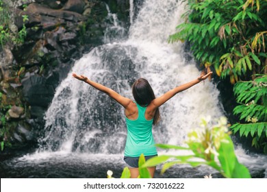 Hawaii travel nature waterfall woman hiker at Canyon Trail Waipoo Falls in Waimea, Kauai island, USA. Freedom happy girl with open arms meditating yoga in rainforest.