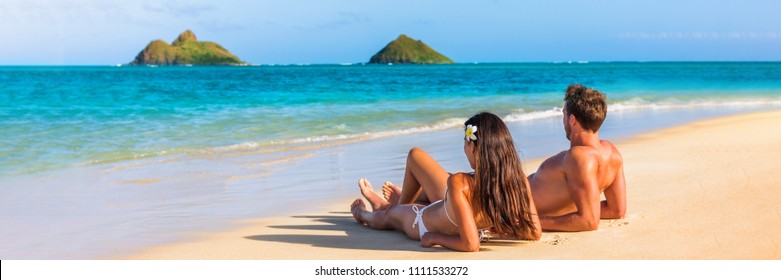 Hawaii Travel Summer Vacation Couple On Hawaiian Tropical Beach In Lanikai, Oahu, Hawaii, US. American Tourists People On Holidays Lying Down, Panoramic Banner Crop With Moke Islands In Background.