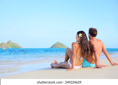 Hawaii Vacation Couple Relaxing Tanning On Beach. Beautiful Young Adults In Love On Hawaiian Holidays Lying Down On White Sand Of Lanikai Beach, Oahu Island, Hawaii, USA.