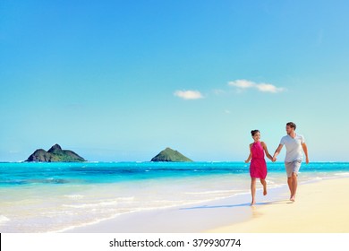 Hawaii Vacation Couple Walking Relaxing On White Sand And Pristine Turquoise Ocean Water On Hawaiian Beach Lanikai, Oahu Island, USA. Holiday Background With Blue Sky Copy-space For Travel Concept.