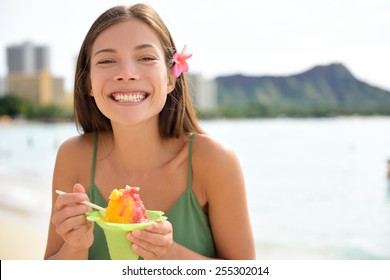 Hawaii Woman On Waikiki Beach Eating Hawaiian Shave Ice, A Local Shaved Ice Dessert. Happy Smiling Mixed Race Asian Caucasian Female Model Enjoying Traditional Hawaiian Snack. Oahu, Hawaii, USA.