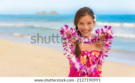 Hawaiian lei girl giving flowers as welcome to Hawaii beach travel vacation destination. Happy Asian woman hula dancer smiling portrait.