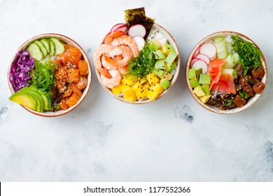 Hawaiian salmon, tuna and shrimp poke bowls with seaweed, avocado, mango, pickled ginger, sesame seeds. Top view, overhead, flat lay, copy space