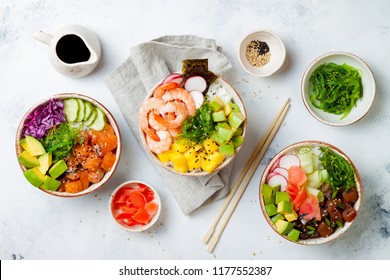 Hawaiian salmon, tuna and shrimp poke bowls with seaweed, avocado, mango, pickled ginger, sesame seeds. Top view, overhead, flat lay - Shutterstock ID 1177552387
